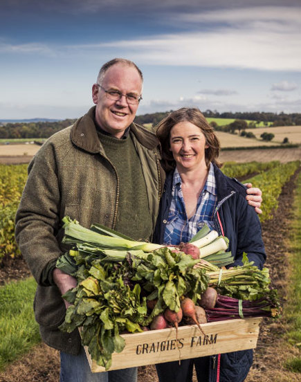 man and woman holding crate of vegetables