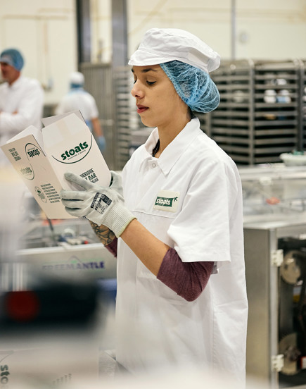 Woman in factory holding box of Stoats